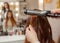 Hairdresser makes hairstyle girl with long red hair in a beauty salon.