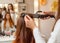 Hairdresser makes hairstyle girl with long red hair in a beauty salon
