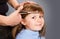 Hairdresser making a hair style to cute little girl