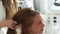 Hairdresser making hairstyle with bouffant and corrugation for young woman with long hair. Hairstylist doing hairdo for
