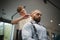 A hairdresser making hairstyle for a man on a barbershop background. Master cutting hair of male in a hairdressing salon