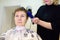 Hairdresser making hairstyle for middle age woman in beauty salon. Short haircut for women