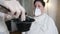 A hairdresser in a mask and baits at home during the virus distributes the dye in a bowl, mixing with a hair brush