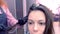 Hairdresser prepare to straights dark brown hair of beautiful woman using hair tongs in beauty salon.