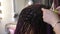 Hairdresser`s female hands professionally braiding a pigtail with a hook close up
