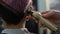 The hairdresser shaves the back of the head of a female client. Rear view of a woman with short pink hair in a