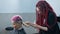 The hairdresser shaves the temple of a female client. Asian woman with short pink hair in barbershop.