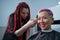 The hairdresser shaves the temple of a female client. Rear view of a woman with short pink hair in a barbershop.