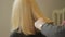 The hairdresser shears a woman with long blond hair. Haircut closeup