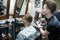Hairdresser shows short haircut with mirror to handsome satisfied client in professional hairdressing salon