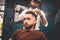 Hairdresser sprays lacquer on client`s hair. barber makes styling a young hipster