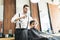 Hairdresser Sprinkles Water On Customer`s Hair In Barber Shop