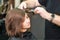 Hairdresser straightening brown hair with hair irons