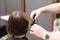 Hairdresser straightening brown hair with hair irons