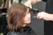 Hairdresser straightening brown hair with hair irons