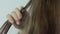 Hairdresser straightening long brown hair with hair irons - closeup