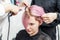 Hairdresser straightening pink hair with hair irons