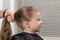 Hairdresser stylist does a girl`s hairdo tail