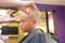 Hairdresser trimming blonde hair of young boy