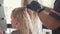 Hairdresser is untangles the hair of blond female customer at beauty spa salon