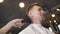 Hairdresser uses brush to cleaning client of cutted hair in barbershop. Male barber using a talc on neck of young guy in