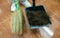 Hairdresser using a broom to sweeping customer hair into a dustpan after cutting hair.