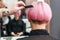 The hairdresser is using comb for female pink hair at beauty salon