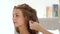 Hairdresser using hairspray while creating curly hairstyle to long haired woman. Hairstylist making curling hair to