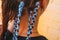 Hairdresser weaves braids with kanekalon material to young girl head, making creative hairstyle with thick plaits or pigtails