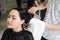 Hairdresser wrapping towel on customer`s head. Brunette woman getting hair treatment in a salon.