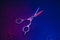 Hairdressing scissors in neon light on a dark background. The tool of the hairdresser