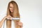 Hairdressing. Woman With Beautiful Long Hair Using Straightener