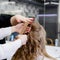 Hairstyle in Hair training center for hairdresser stylist. Hairdresser making hairstyle to blonde hair woman with long hair in