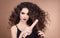 Hairstyling. Curly Beauty hair. Glamour portrait of beautiful woman model holding straightening iron. Brunette with marsala matte