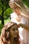 Hairstylist braiding pigtails to young girl outdoor. Creating braids.