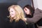 Hairstylist combing female client blond girl in hairdressing salon