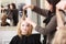 Hairstylist combing female client blond girl in hairdressing salon