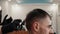 Hairstylist combing wet male hair before cutting in male salon. Bearded man getting stylish haircut in barbershop