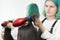 Hairstylist drying brunette hair with red hair dryer, blue hairbrush in beauty salon