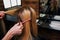 Hairstylist hands holding strand of blonde hair while combing it before haircut in salon