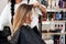 Hairstylist makes a hairstyle for a woman with light brown long hair