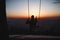 Hairy young boy aged 16-20 of European descent enjoys his life swinging on a swing at sunset on the top of Prasiva mountain