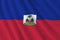 Haiti flag with big folds waving close up under the studio light indoors. The official symbols and colors in banner