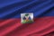 Haiti flag with big folds waving close up under the studio light indoors. The official symbols and colors in banner