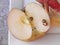 Half apple part with apple slices on a white saucer with apple peel, peeling organic red Pink Lady apple, on a table