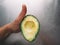 Half an avocado in a hand on the background of a steel table top view horizontal, fresh healthy food breakfast on kitchen