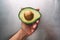 Half an avocado in a hand on the background of a steel table top view horizontal, fresh healthy food breakfast on kitchen