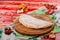 Half of the baked calzone - closed type of pizza that is folded in half, on round wooden board on red wooden background