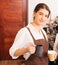 Half-body right side angle of beautiful caucasian barista women fills white milk into takeaway hot coffee cup at coffee bar in