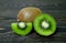 Half bright juicy ripe beautiful kiwi, a piece of kiwi and a whole kiwi on a coarse dark wooden background from boards